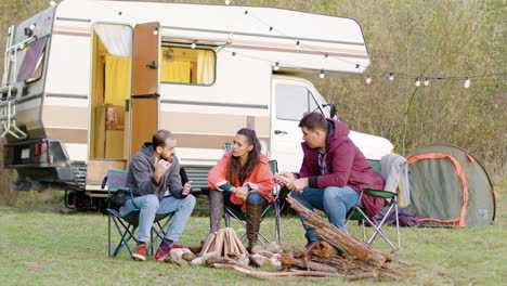 man telling a story to his friends sitting on camping chairs