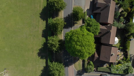 Toma-Aérea-Mirando-Hacia-Abajo-Sobre-El-Frondoso-Barrio-Suburbano-Con-Coches-Y-Furgonetas-Pasando