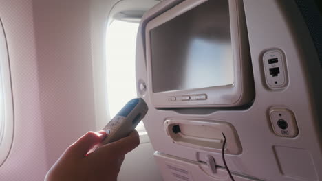 un niño con una máscara protectora usa la pantalla de entretenimiento en el avión