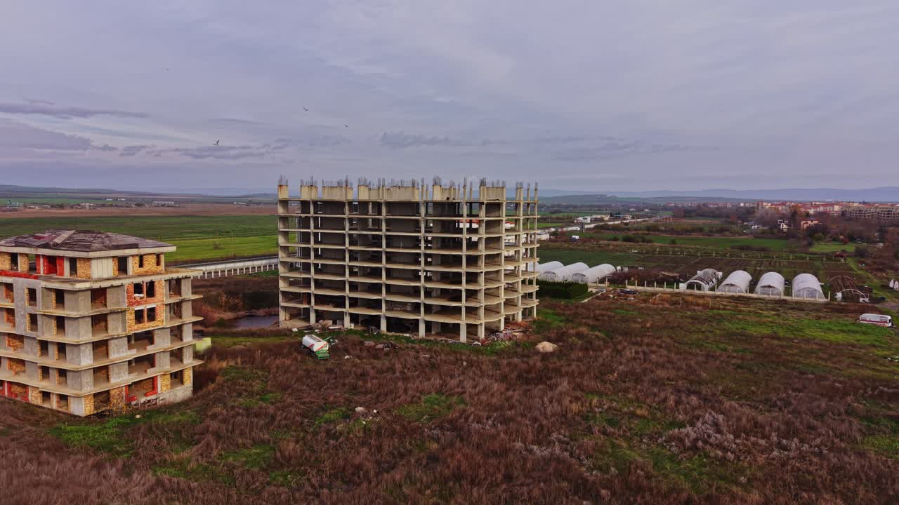 Construction site of abandoned building surrounded by fields
