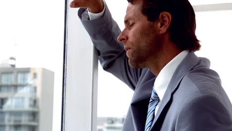 unhappy businessman looking out window