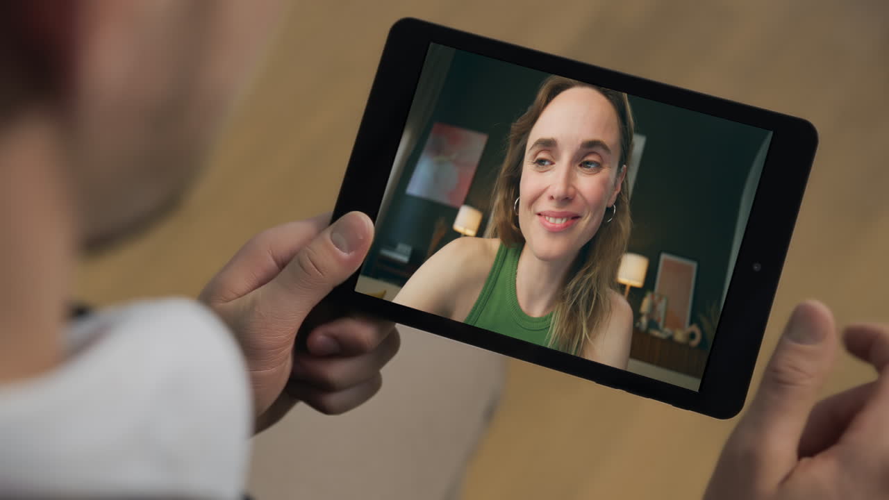 Primo piano di un fidanzato che flirta durante una videochiamata su tablet a casa. Incontro virtuale di coppia