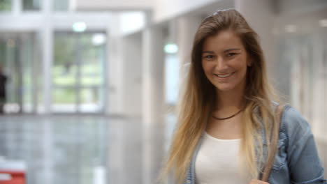 Female-university-student-in-a-modern-lobby-walks-into-focus