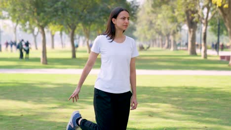 Niña-India-Haciendo-Estiramientos-De-Piernas-Para-Correr-En-Un-Parque-Por-La-Mañana