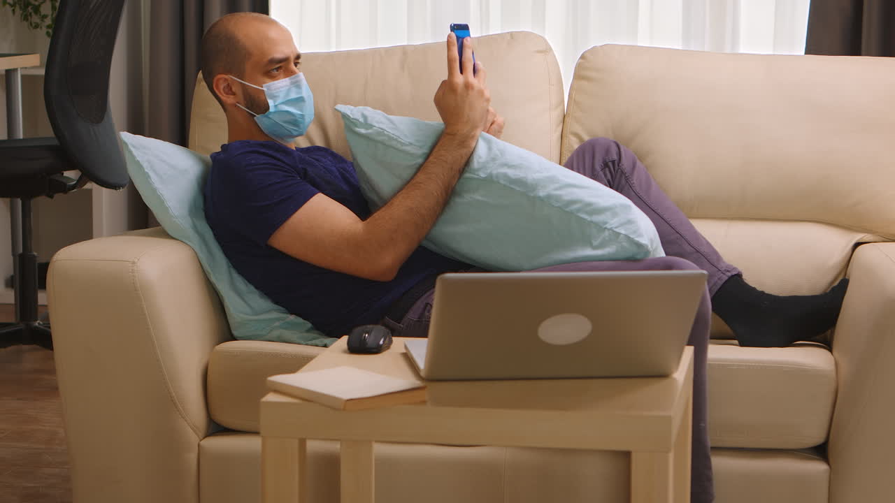 Man with disposable mask on sofa