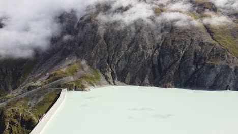 view-from-the-side-of-the-large-dam-wall-of-the-lac-des-dix-with-fast-moving-clouds,-bright-colors