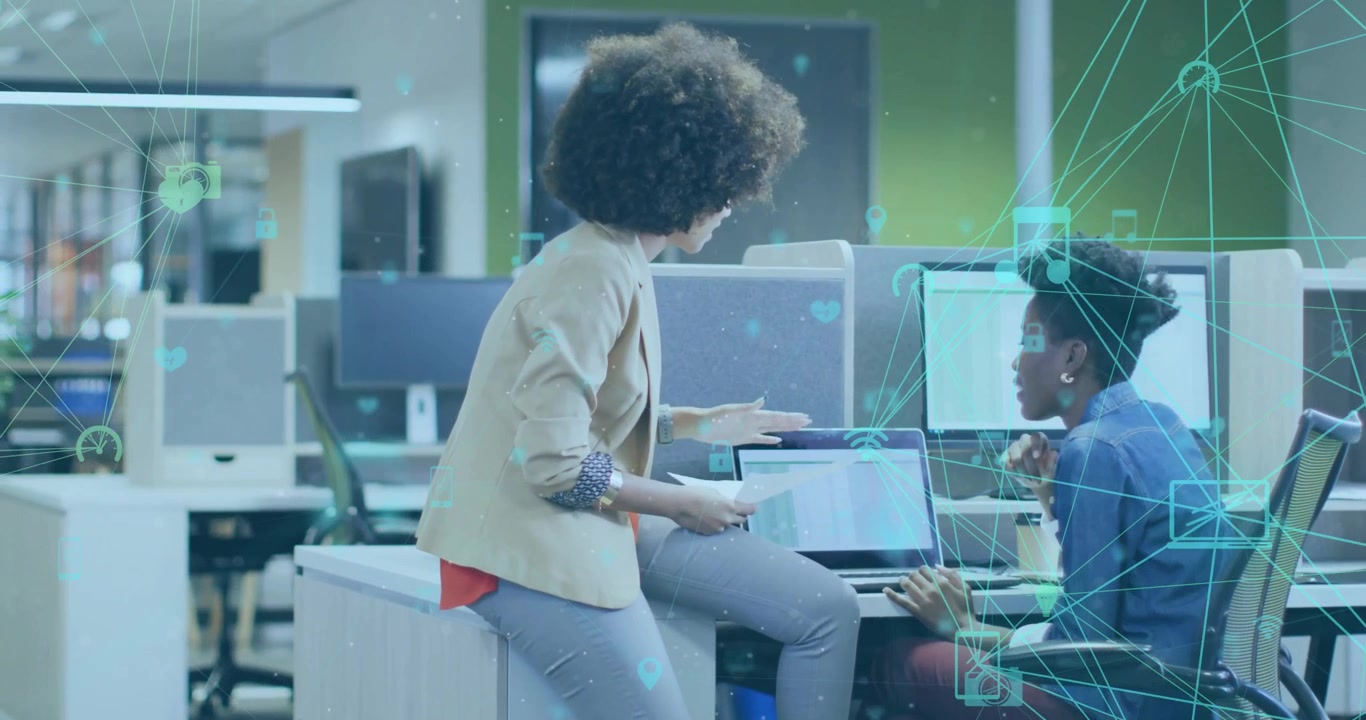 Female colleague flipping report and tapping laptop chart while icons animating for business review