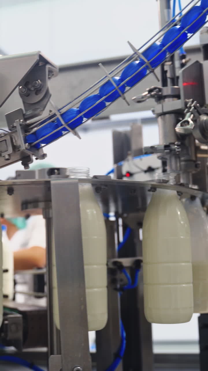 Production line at modernized dairy factory. Automated production line at milk factory. Milk pouring into plastic bottle at dairy plant. Vertical video