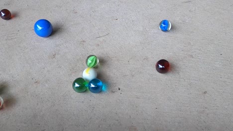 primeros planos de canicas de colores golpeando un suelo de hormigón gris