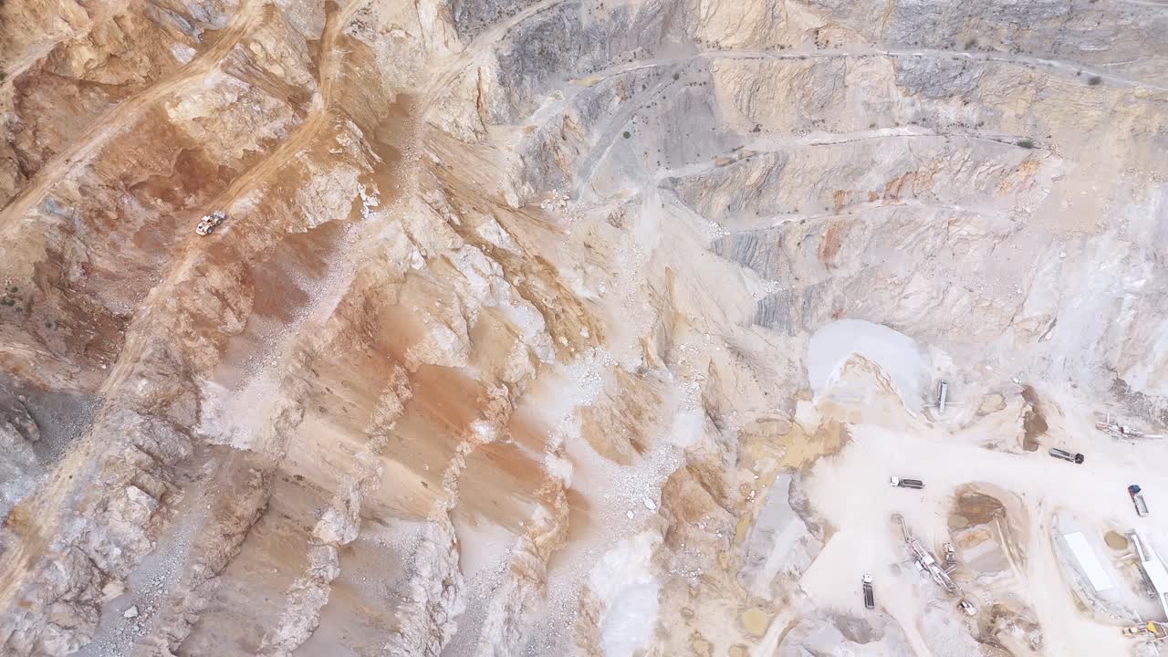 A Large Quarry Site Shows Heavy Machinery Extracting Minerals From the Steep, Terraced Landscape - Orbit Drone Shot