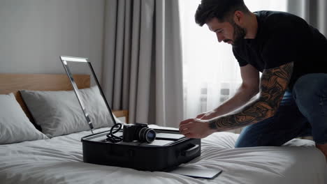 man packing suitcase on bed