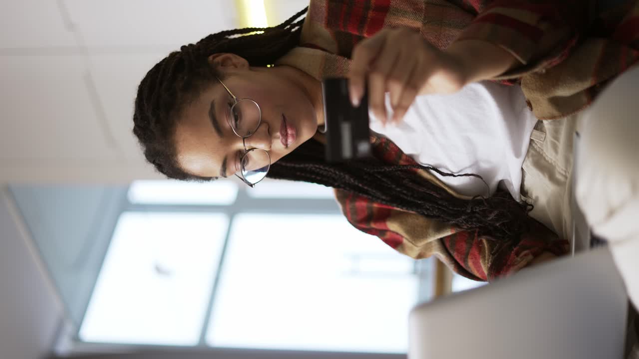 joven afroamericano con tarjeta de crédito usando computadora portátil y comprando en línea, de cerca