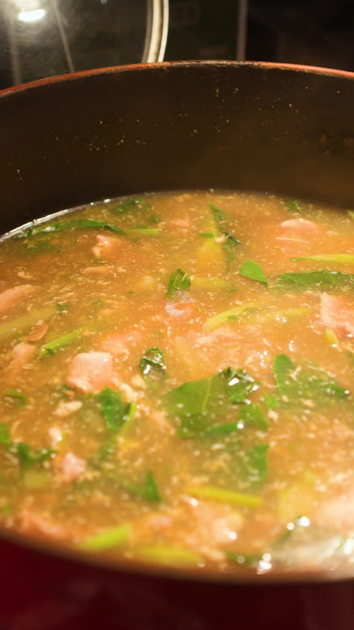 L'illuminazione calda illumina una zuppa di pesce thailandese bollente all'interno di una pentola di ferro rustica.