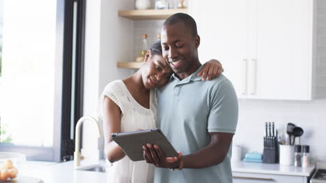 a diverse couple is using a tablet in the kitchen at home