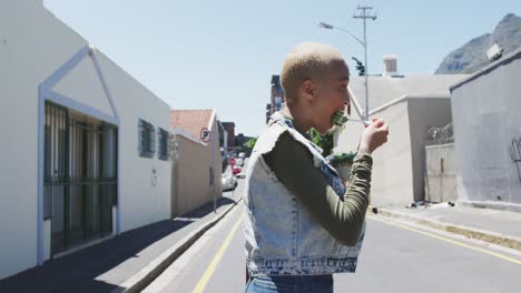 mixed race woman crossing a street and eating a takeaway salad lunch