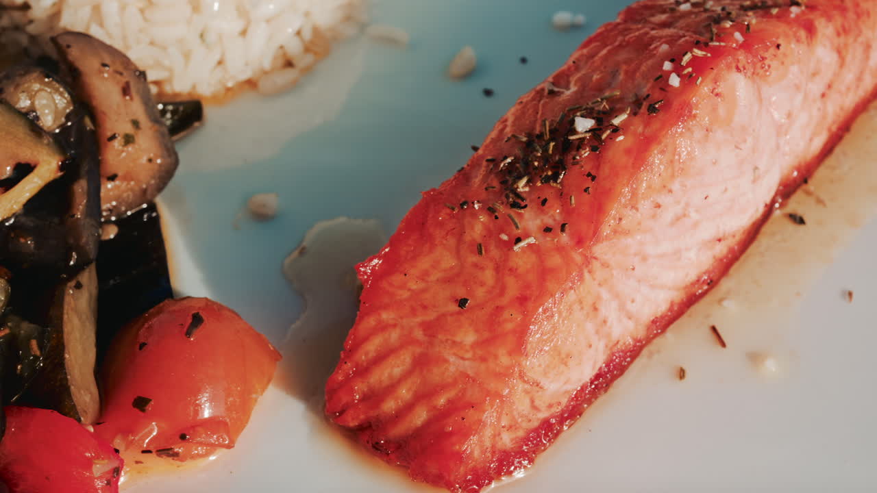 A balanced restaurant dish featuring grilled salmon fillet, white rice, lemon, and mixed vegetables
