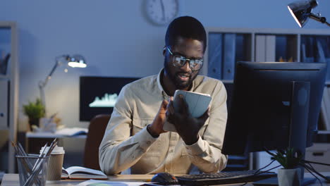 young businessman texting on the tablet in the office at night