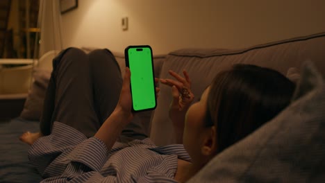 mujer usando el teléfono en el sofá por la noche