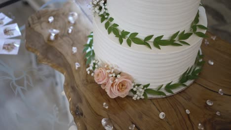 pastel de boda blanco adornado con flores frescas y vegetación.