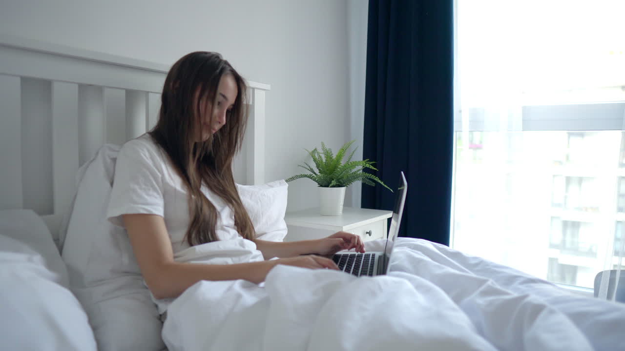침대에 노트북으로 일하는 여자