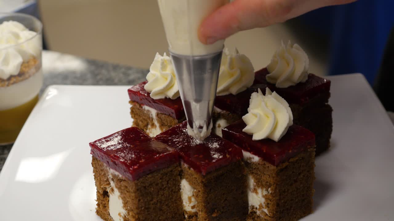 Chef Decorating Small Cakes with Whipped Cream and Raspberry Jam