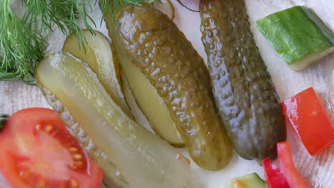 closeup of pickled cucumbers, tomatoes, red bell pepper, and dill on a plate