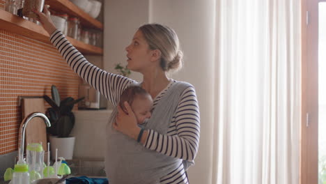 junge mutter hält ihr schlafendes baby zu hause, putzt in der küche, arbeitet im haushalt, genießt die verantwortung als mutter, kümmert sich um das kind