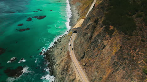 dangerous road coming by the middle of the mountain. stunning view of the azure pacific ocean meeting rocky coastline. aerial perspective.