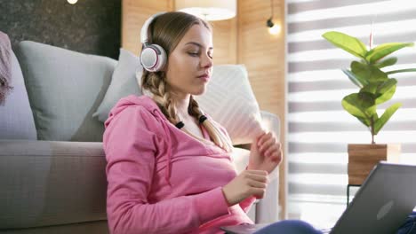 slow motion shot of beautiful teenage woman relaxing at home alone putting on headphones and enjoying music