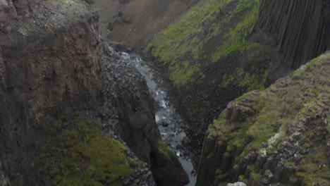 cinematic drone flight over cliffs and waterfall of iceland during daytime - tilt down shot
