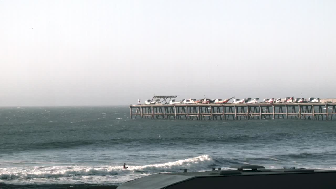 바다 위에 보트가 있는 목조 부두, 해변에서 구르는 파도