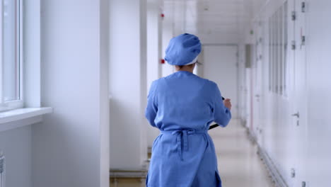 Woman-driving-pallet-jack-in-white-corridor.-Factory-warehouse-working