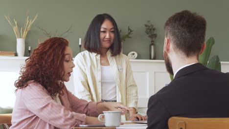 group of three multiethnic colleagues sitting at table and debating about work during a team meeting 1