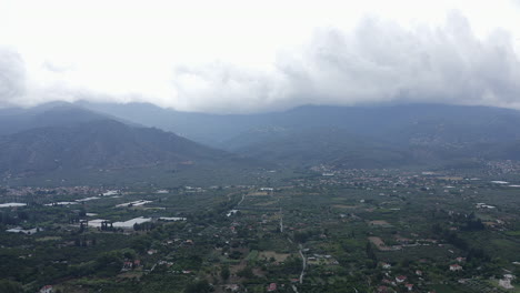 Misty-overcast-aerial-rises-over-green-agriculture-fields-in-Greece