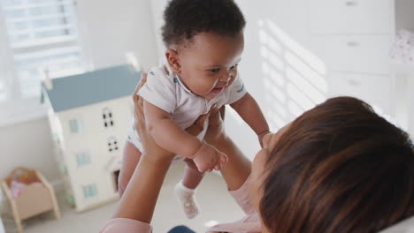 Proud-Grandmother-Cuddling-And-Playing-With-Baby-Grandson-In-Nursery-At-Home