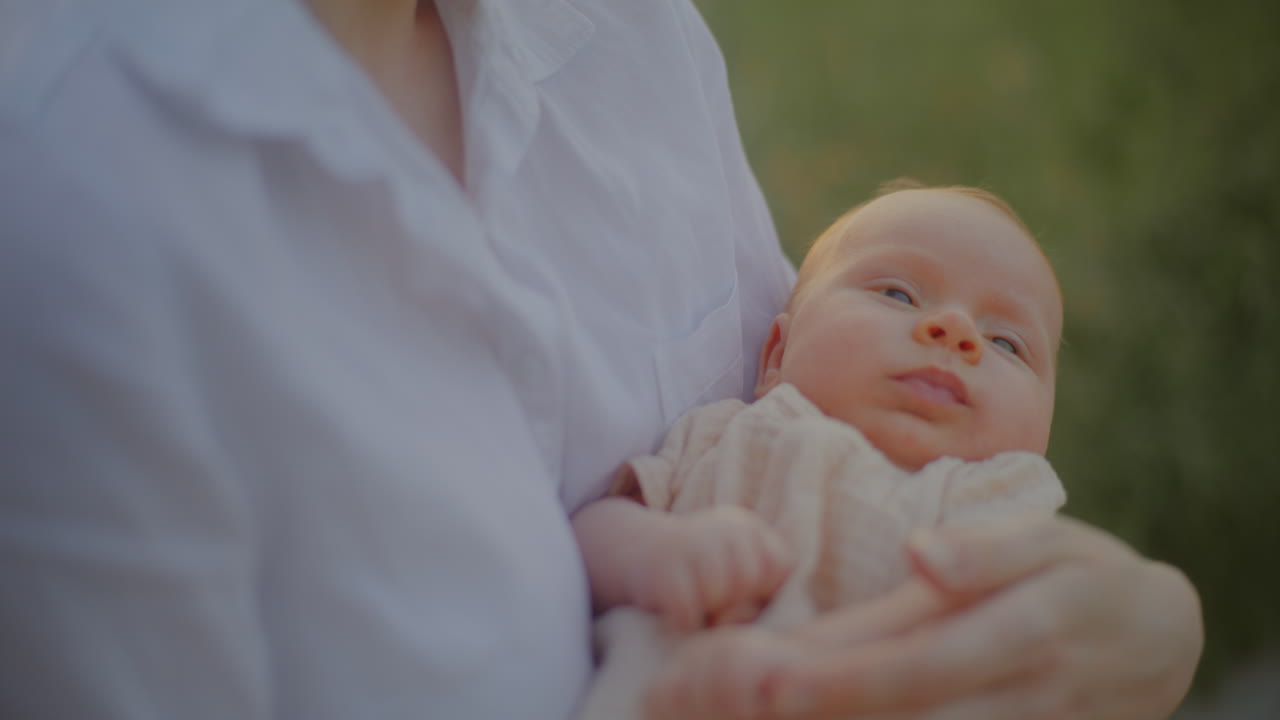 Smiling Woman Holding Newborn at Sunset