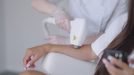 Procedure-of-removing-hairs-on-hand.-Laser-hair-removal-on-a-diode-laser-tracking-moving-camera.-Woman-cosmetologist-applies-laser-hair-removal-gel-on-female-hand.-photoepilation-body-care-concept.