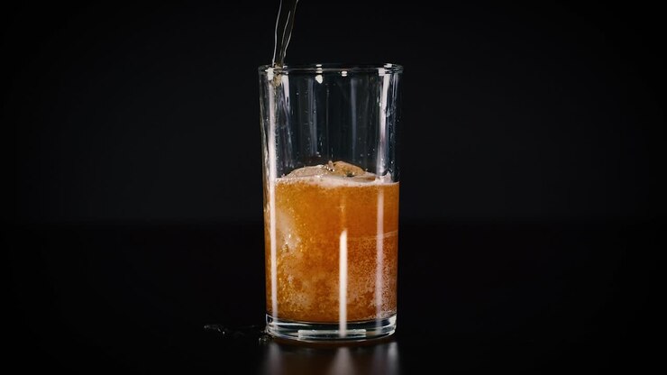 limettengetränk in ein glas auf schwarzem hintergrund gegossen