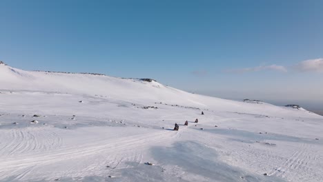 Luftpanorama-Landschaftsansicht-Von-Menschen,-Die-An-Einem-Sonnigen-Abend-Auf-Dem-Eisigen-Boden-Eines-Gletschers-In-Island-Mit-Schneemobilen-Unterwegs-Sind