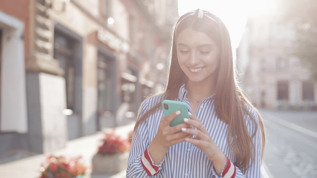 Giovane donna che parla al telefono e sorride per strada.