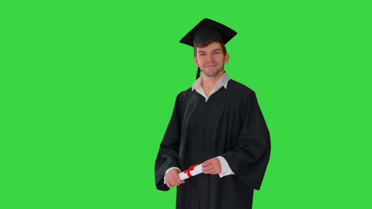 Happy male student in graduation robe waiving with his diploma on a Green Screen, Chroma Key