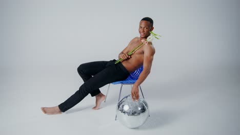 hombre posando con flores y bola de discoteca