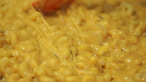 pov closeup video shows a silicone spatula stirring the most creamy, rich and delicious macaroni and cheese