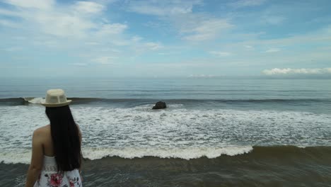 Woman-standing-on-the-edge-of-a-cliff-overlooking-the-sea_drone-shot