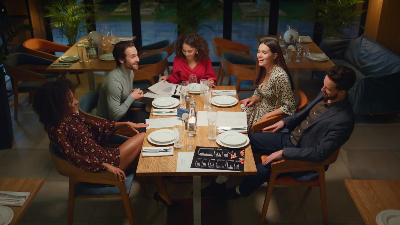 Multiethnic friends group celebrating having fun in evening fancy restaurant.