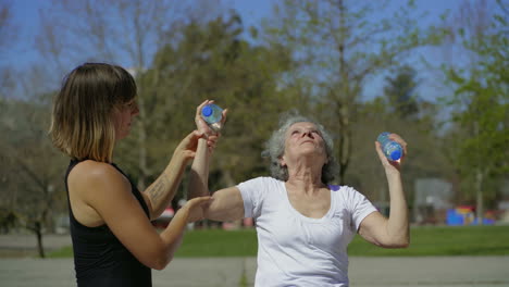 sporty senior woman training in park with coach.