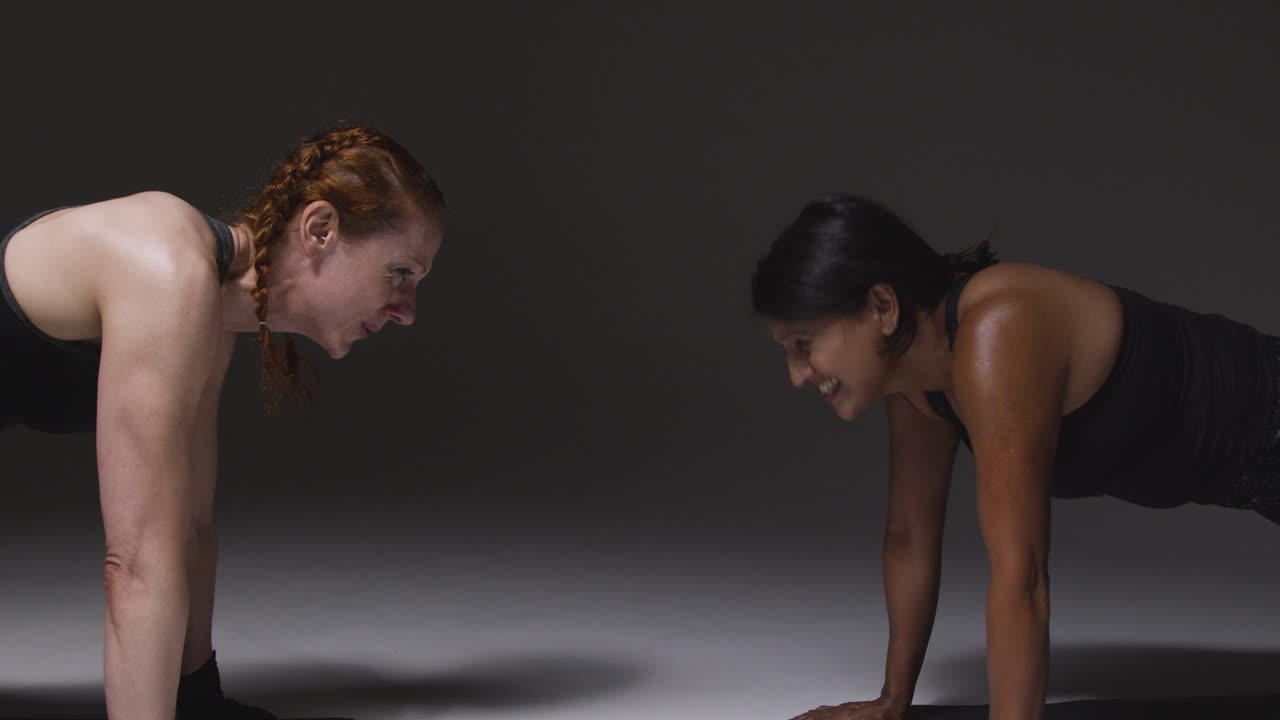 Studio Shot Of Two Mature Women Wearing Gym Fitness Clothing Doing Plank Exercise Together 3