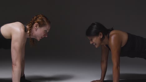 Studio-Shot-Of-Two-Mature-Women-Wearing-Gym-Fitness-Clothing-Doing-Plank-Exercise-Together-3