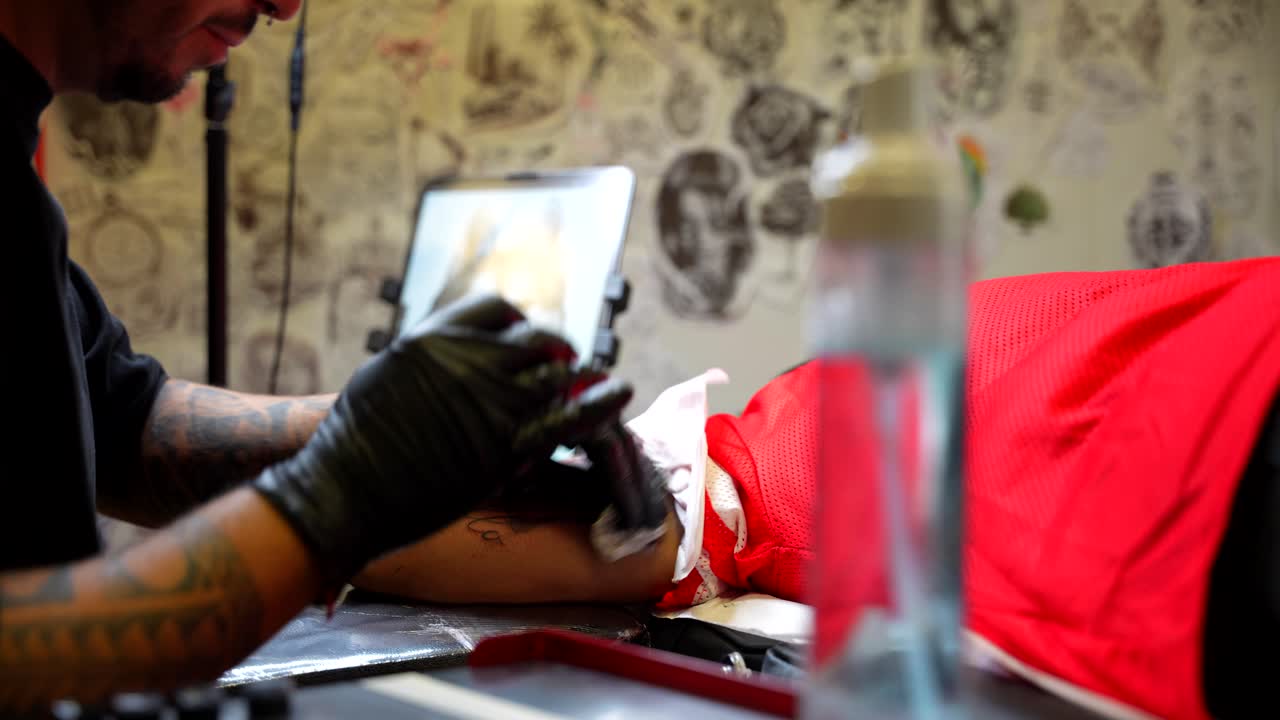 Tattoo artist finishes ink design while cleaning the skin with foam in a studio setting