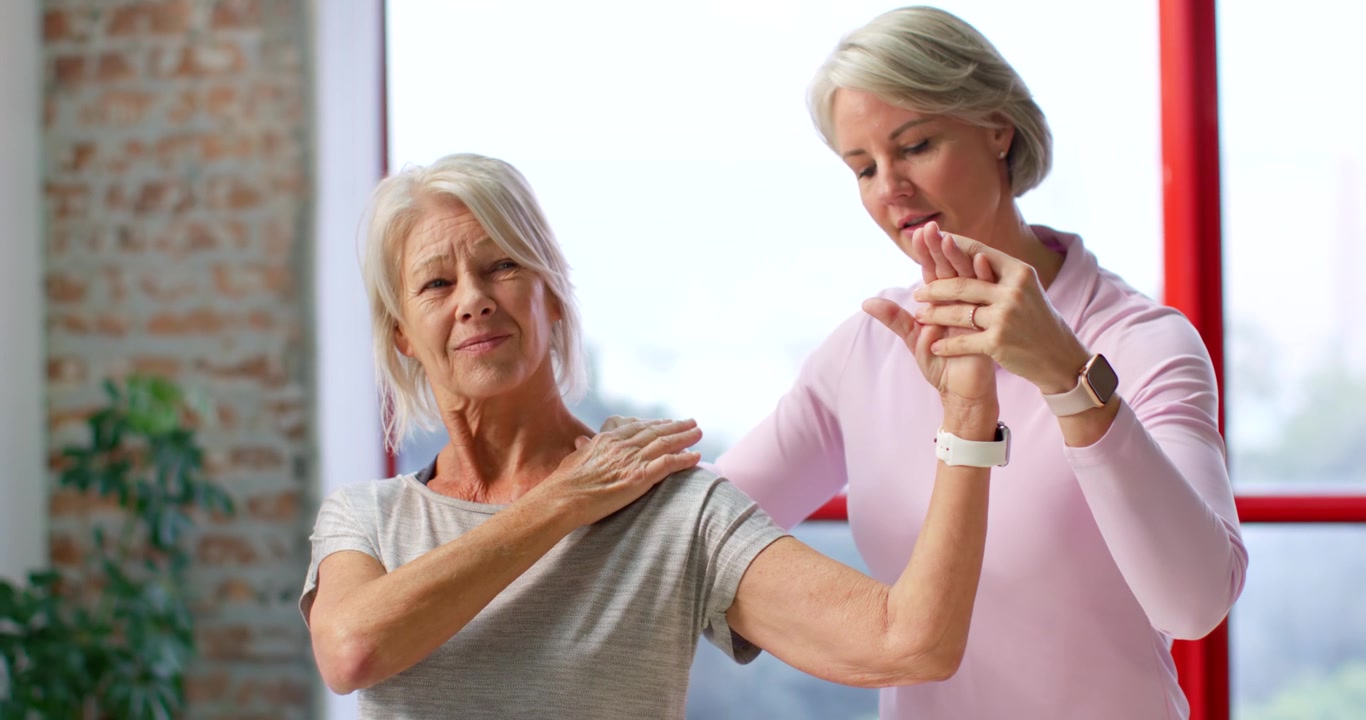 Senior woman and therapist after pain guiding arm rotation in clinic using hands for mobility